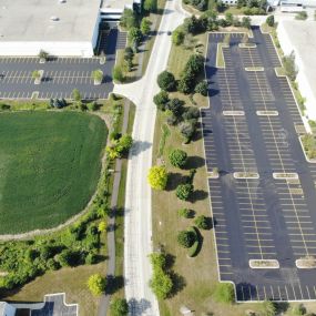 Aerial view of a freshly repaved and painted parking lot with trees and grass seen to the left.