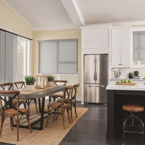 Bring your open floor plan together with flawlessly coordinated window treatments. This kitchen and dining area comes together with attractive Roller Shades and Sliding Panel Track Blinds for the patio door. #Budget BlindsParamusWestwood #PanelTrackBlinds #BlindedByBeauty#RollerShades  #ShadesOfBeau