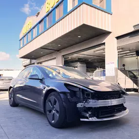 Detailed photo of Tesla Model 3 waiting at auto body shop parking lot for collision repair