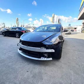 Detailed photo of Tesla Model 3 waiting at auto body shop parking lot for collision repair