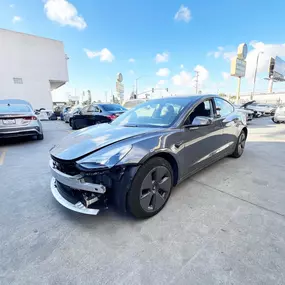 Detailed photo of Tesla Model 3 waiting at auto body shop parking lot for collision repair