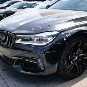 Detailed photo of BMW sedan waiting at auto body shop parking lot for collision repair