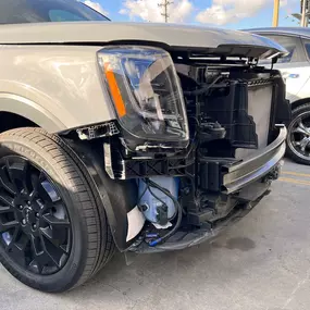 Detailed photo of Kia SUV waiting at auto body shop parking lot for collision repair