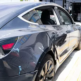 Detailed photo of Tesla Model 3 waiting at auto body shop parking lot for collision repair