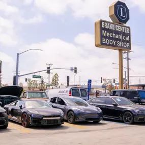 Line up of cars waiting for collision repair at LUXE Auto Body Shop