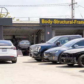 Line up of cars waiting for collision repair at LUXE Auto Body Shop