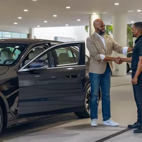 2 people shaking hands by a blue BMW at BMW of Pembroke Pines