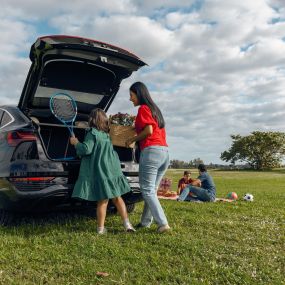 Family on a picnic getting items from the truck of a New Audi