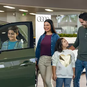 Family in the showroom at Audi Pembroke Pines looking at a New Audi at Audi of Pembroke Pines in Florida