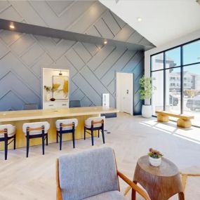 Spacious resident seating area with a wooden table and cozy chairs, perfect for working from home, completed by oversized windows and a navy patterned wall design