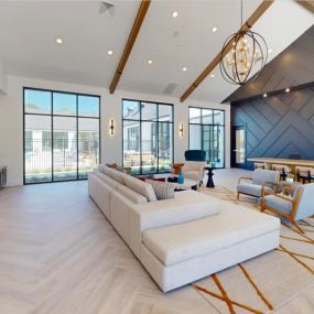 Resident lounge area with herringbone wooden flooring, a cream couch, and a large table surrounded by chairs