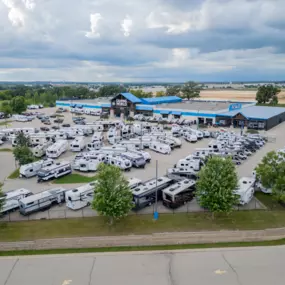 aerial view of Camping World in Madison, WI showing the building and many RVs in front of it, the sky and many trees and a Camping World sign