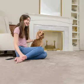 girl sitting on carpet with dog