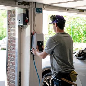 1KOMMA5°-Installateur montiert eine zukunftsweisende Elektrofahrzeug-Ladestation (Wallbox) in einer Garage, um die E-Mobilität zu fördern