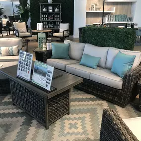 Stylish wicker patio seating set with aqua cushions and a dark wood coffee table.