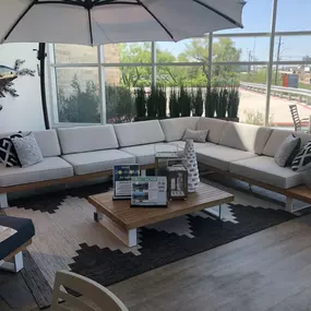 Modern white and wood outdoor sectional with a sleek coffee table and large patio umbrella.