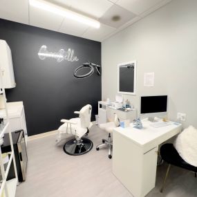 A single esthetician salon suite in Denver, Co showcasing custom storage,  painted walls and neon signs.