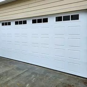 New white garage door installation in West Point, Utah. Professionally installed by Beacon Garage Doors, featuring a modern paneled design with decorative windows for enhanced curb appeal and security.