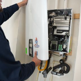 A picture of a man removing the cover of a tankless water heater