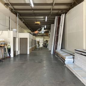 A picture of the space at Unlimited Garage Door Services. Garage door panels stacked up on the floor and doors to rooms in the back to the left side