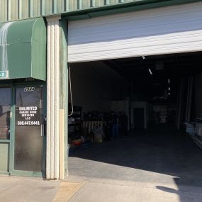 A picture of the front door of Unlimited Garage Door Services with the garage door open showing the supplies inside