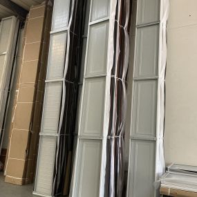 A picture of long garage door panels stacked up vertically against a wall