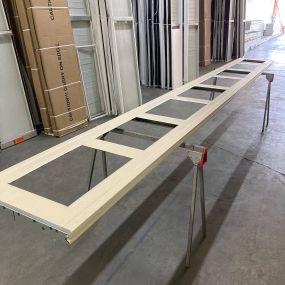 A picture of a long garage door panel laying on saw horses with holes cut for windows
