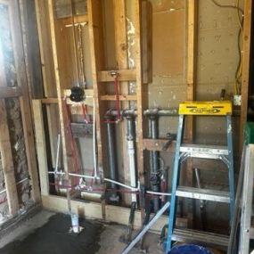 A picture of an a wall with exposed studs, water lines and electrical lines.