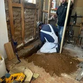 A picture of an exposed wall with men working on something on the ground