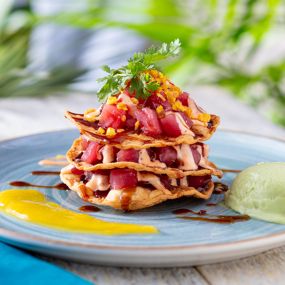 NEW! Tuna Tostada Stack - Ahi tuna poke layered with crispy tortillas, drizzled with a zesty lime aioli, served with avocado.