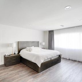 Bright and airy rehab bedroom featuring modern decor, white furniture, and a large window that floods the room with natural light. This fresh and inviting bedroom design creates a comfortable and healing environment for clients.