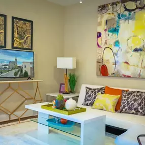 A living room with a white coffee table and colorful pillows