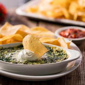 Santa Fe Spinach Dip: Prepared with creamy cheese, topped with sour cream and served with freshly fried tortilla chips and a side of salsa.