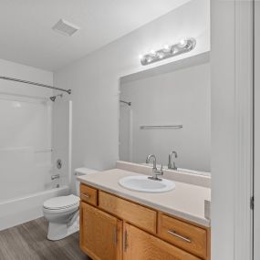 Bathroom with wooden vanity area, single sink, and above-mirror lighting
