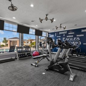 Resident Fitness Center with natural light and a wall of windows overlooking the pool