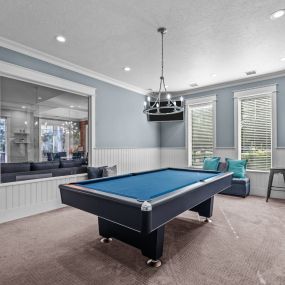 a game room with a pool table with pendant lighting and a window