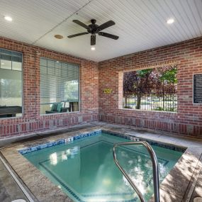 the indoor spa with brick walls and a ceiling fan