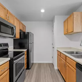 Kitchen area with wooden-style cabinets, plank flooring, and recessed lighting