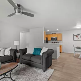 Living room with two grey couches, coffee table, and area rug, with plank flooring and view into dining area