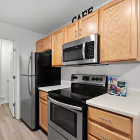 Kitchen with wooden cabinetry, plank flooring, and sleek appliances