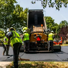 Dominion Paving Contractors Laying And Smoothing Asphalt On Street