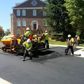 Dominion Paving Contractors working together applying new and fresh asphalt to a road