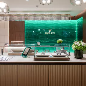 The walls are meticulously lined with wood and limestone tiles in which every grain is aligned seamlessly, creating the impression every wall is cut from a single block of wood.  Surrounding these walls is a medley of glass and light that play off each other to create an immersive experience that instantly pulls you into the world of Rolex. Along the backwall of the showroom lies  a beautiful wave of Rolex green glass – currently the only boutique wall with a 90 degree corner in glass in the cou