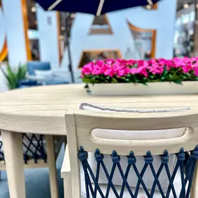 Elegant outdoor dining set with floral centerpiece under a black umbrella.