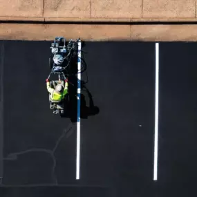 Blue Curb LLC Contractor Lining Up the Parking Space Lines in a Freshly Paved Parking Lot