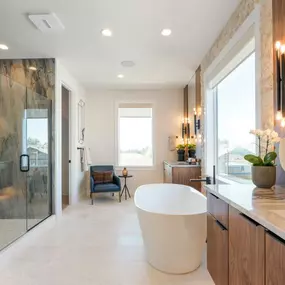 Spa-like primary bathroom with separate floating vanities and free-standing tub