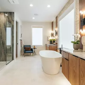 Primary bathroom boasts separate floating vanities, a free-standing tub, and large walk-in shower