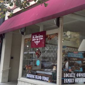 Exterior of the Kilwins Traverse City, MI 49684 chocolate, fudge, and ice cream store with store signage on the clear glass windows