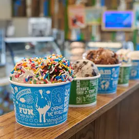 Multiple ice cream cups on a railing in a Ben & Jerry's ice cream shop.