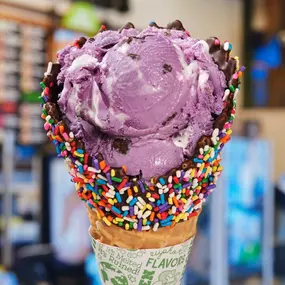 UltraViolet Ice Cream Flavor in Waffle cone at a Ben & Jerry's ice cream shop. UlrraViolet is Vanilla Ice Cream with Marshmallow Swirls, Gluten-Free Chocolate Cookies & Fudge Flakes.
